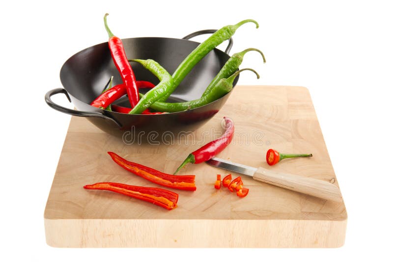 Fresh red and green hot chili peppers in black wok pan isolated over white