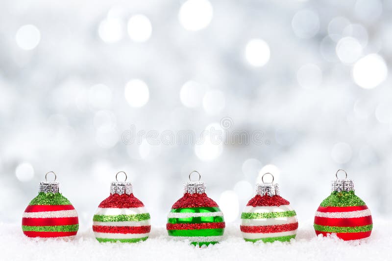Red, green, white Christmas ornaments in snow with twinkling background