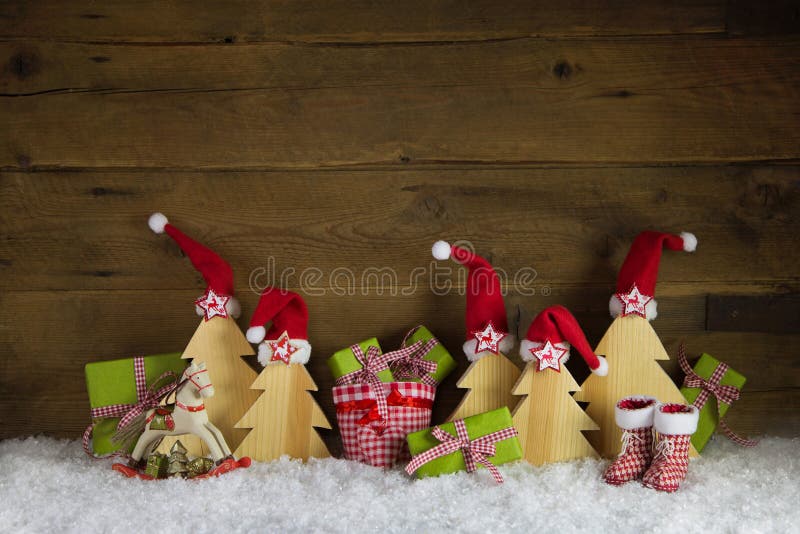 Red, green, yellow and brown christmas background with presents, rocking horse and santa hats on wood with snow.