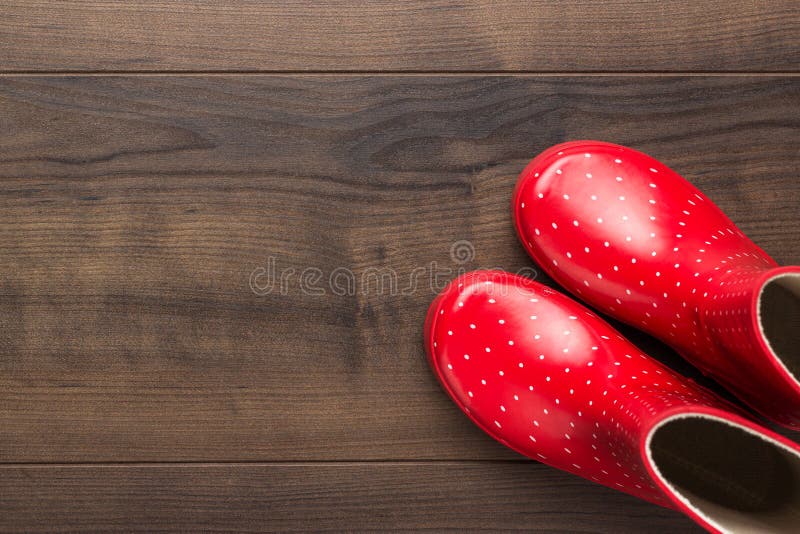 New red children`s stylish gumboots with some copy space. overhead shot of watertights on wooden floor royalty free stock images New red children`s stylish gumboots with some copy space. overhead shot of watertights on wooden floor royalty free stock images