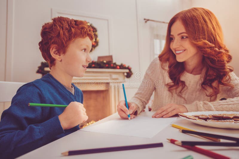 Red-haired boy and his mother drawing gingerbread man together stock photo Red-haired boy and his mother drawing gingerbread man together stock photo