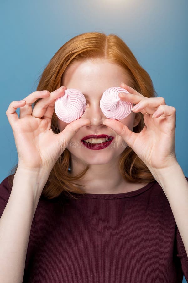 Red haired girl covered her eyes with marshmallows. Smile, positive emotions, fun, close-up portrait stock photos Red haired girl covered her eyes with marshmallows. Smile, positive emotions, fun, close-up portrait stock photos