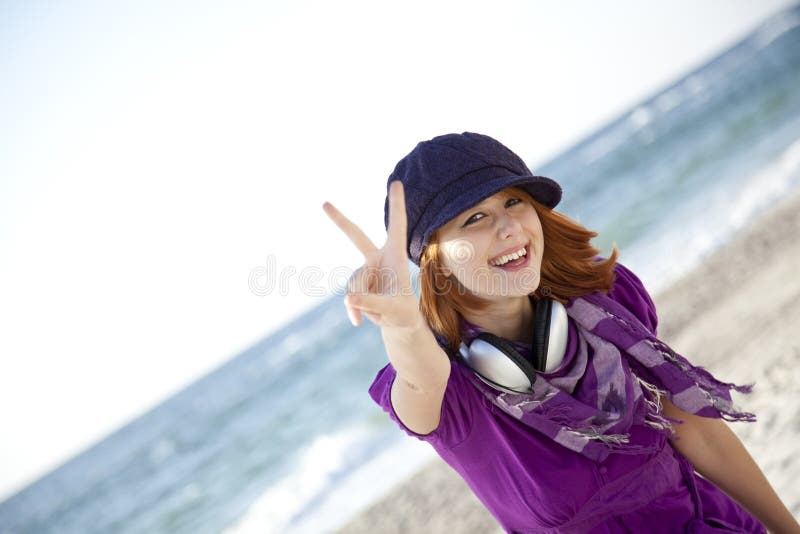 Red-haired girl with headphone on the beach.