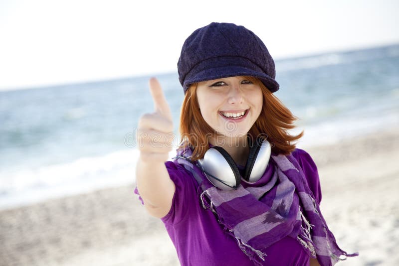 Red-haired girl with headphone on the beach.