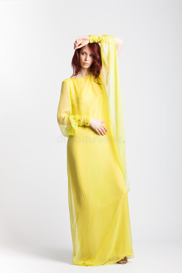 Red-haired girl in long elegant yellow dress