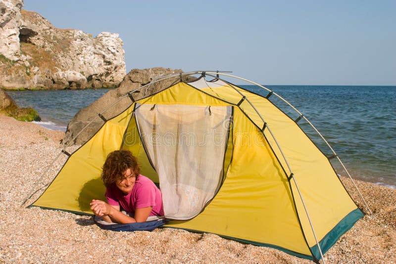 Red-haired girl in sleeping-bag near of tent