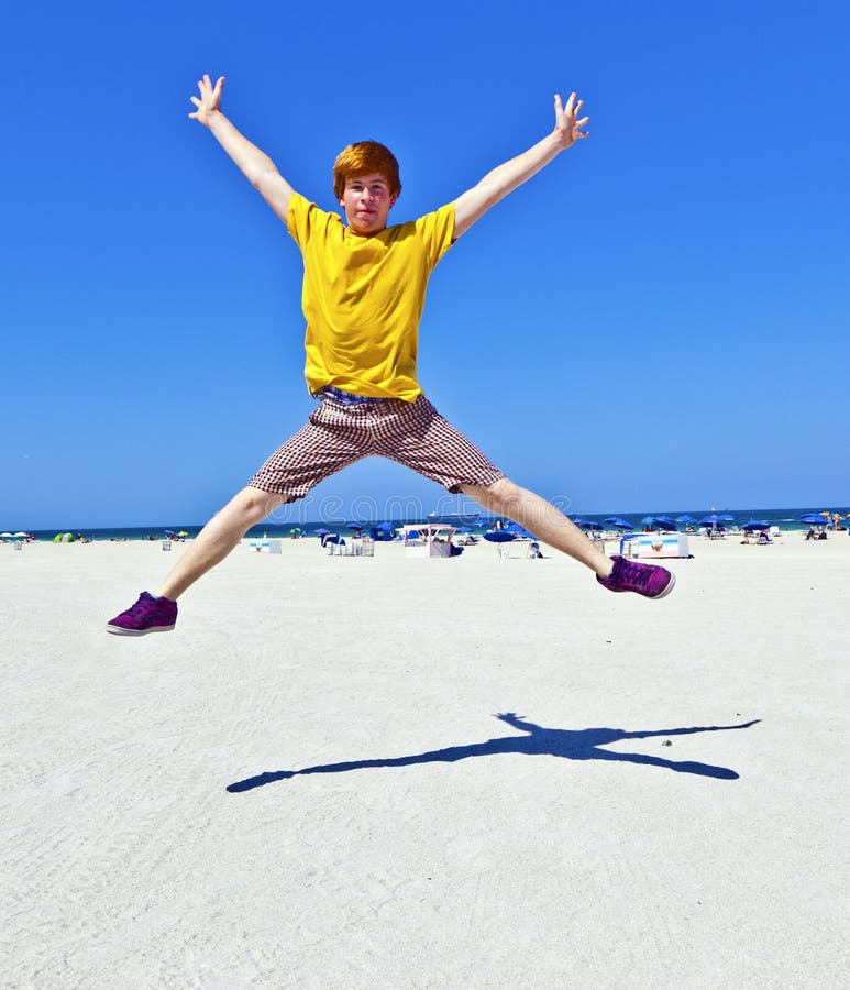 Red-haired teen boy jumping at the beach in Miami