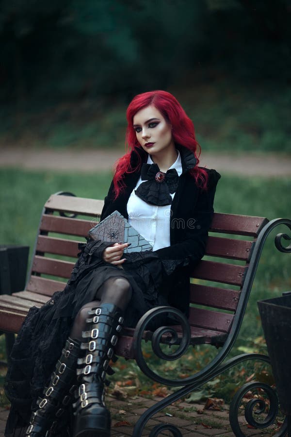 Red haired vampire girl in an old Museum in Gothic black clothes and a tailcoat dark book spider