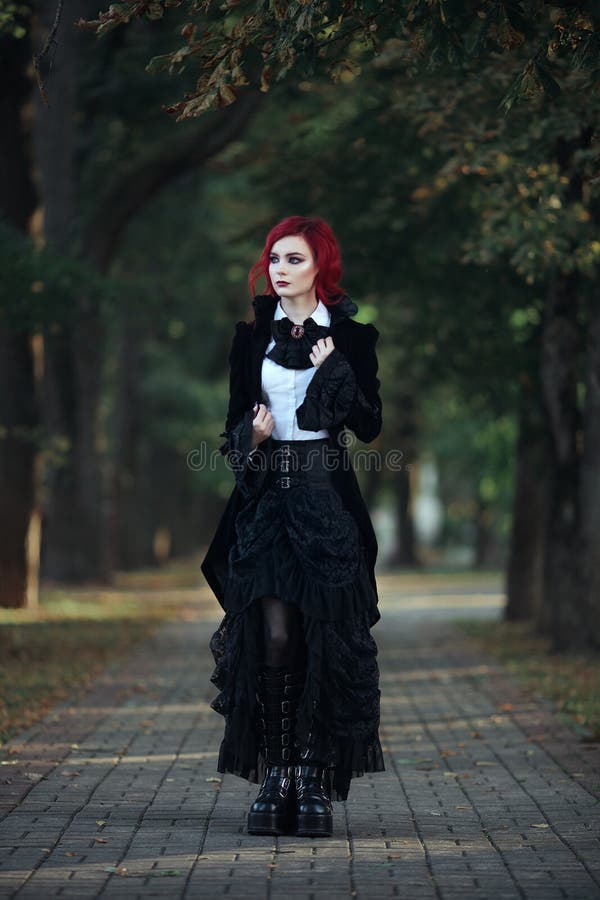 Red haired vampire girl in an old Museum in Gothic black clothes and a tailcoat