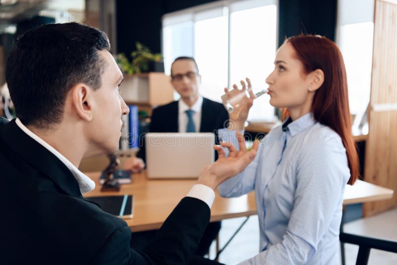 Red-haired woman is drinking glass of water, sitting next to adult man in divorce lawyer`s office. stock photos Red-haired woman is drinking glass of water, sitting next to adult man in divorce lawyer`s office. stock photos