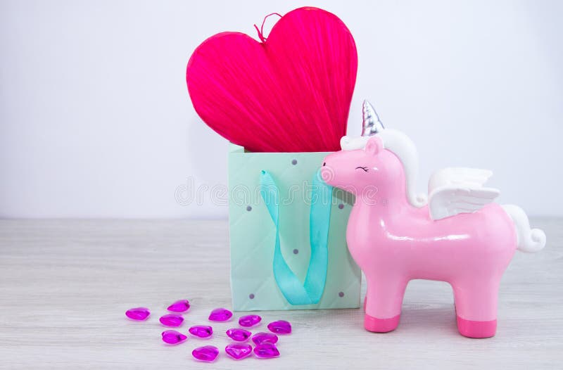 Red heart in a gift box. Toy pink unicorn on a light background. Valentine`s day gift stock image Red heart in a gift box. Toy pink unicorn on a light background. Valentine`s day gift stock image
