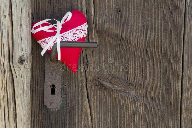 Red heart shape hanging on door handle or a wooden Background, c