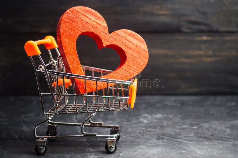 Red heart in the supermarket trolley. concept of buying love. Valentine`s Day. yellow background. Love of shopping. Favorite stor