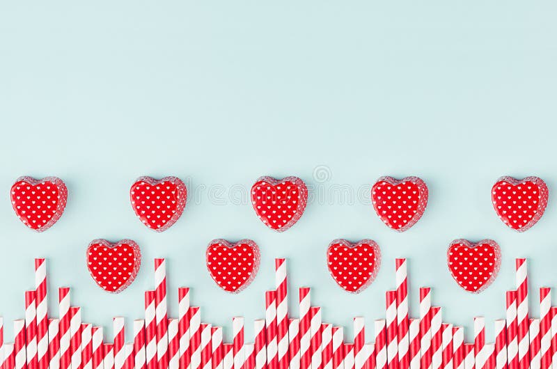 Red hearts and striped straws border with copy space on trendy color mint backdrop as playful modern valentine`s day background. stock images