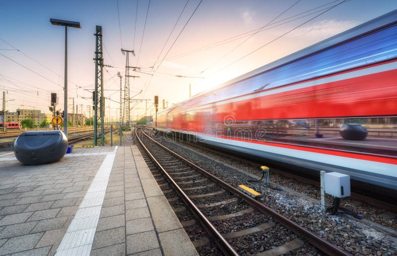 Red high speed train in motion on the railway station