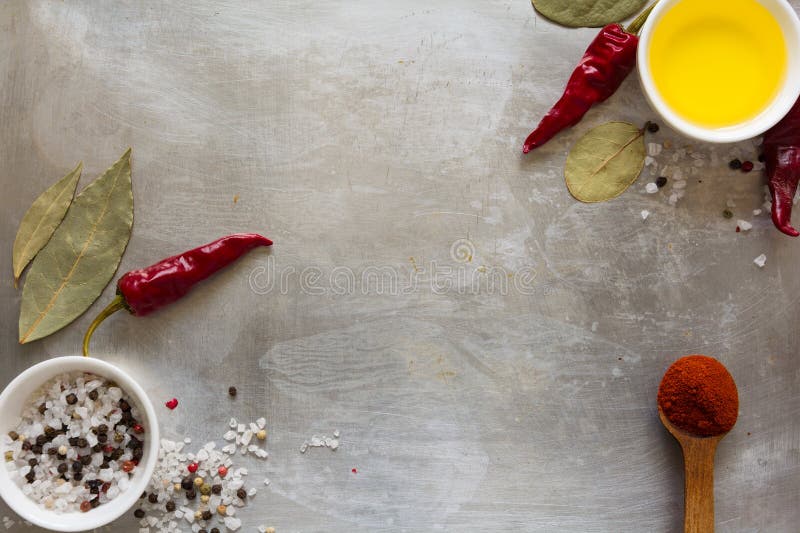 Red hot chili pepper pods peas, salt, oil and bay leaves on grey vintage metal culinary background