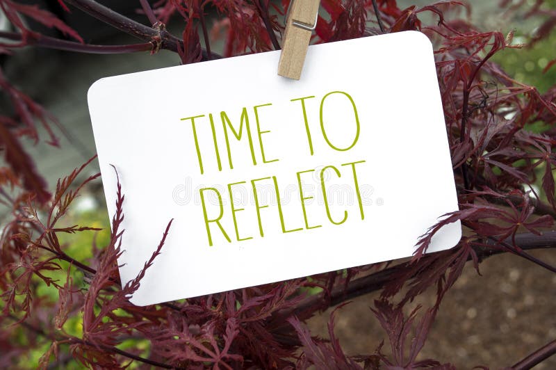 Red japanese maple with white paper board shwoing the message Time to Reflect
