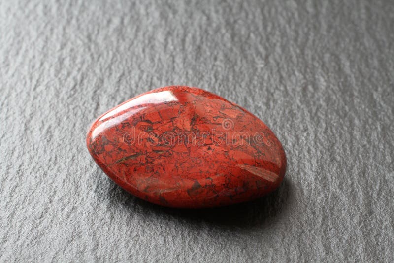 Red jasper stone on a black stone board. Closeup.