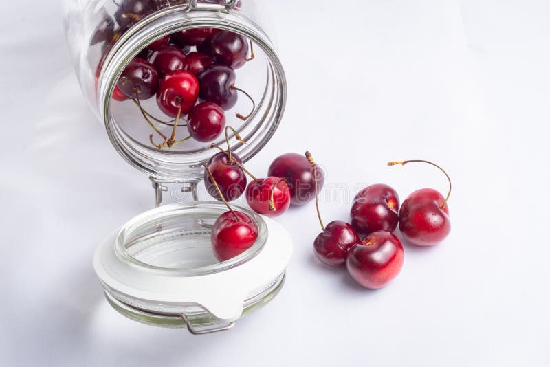 Red and Juicy Cherries in the Glass Jar on the White Background Stock
