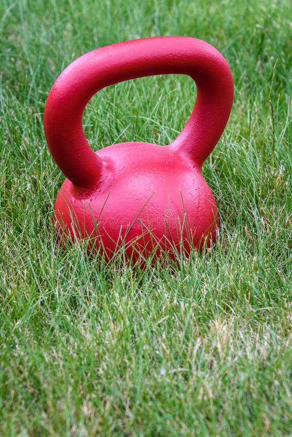 Red Kettle Bell on a Green Lawn, Ready for an Outdoor Workout Stock