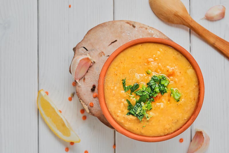 Red lentil soup with ingredients on wooden white plate, top view with copy space. Traditional Turkish or Arabic Lentil Vegetable