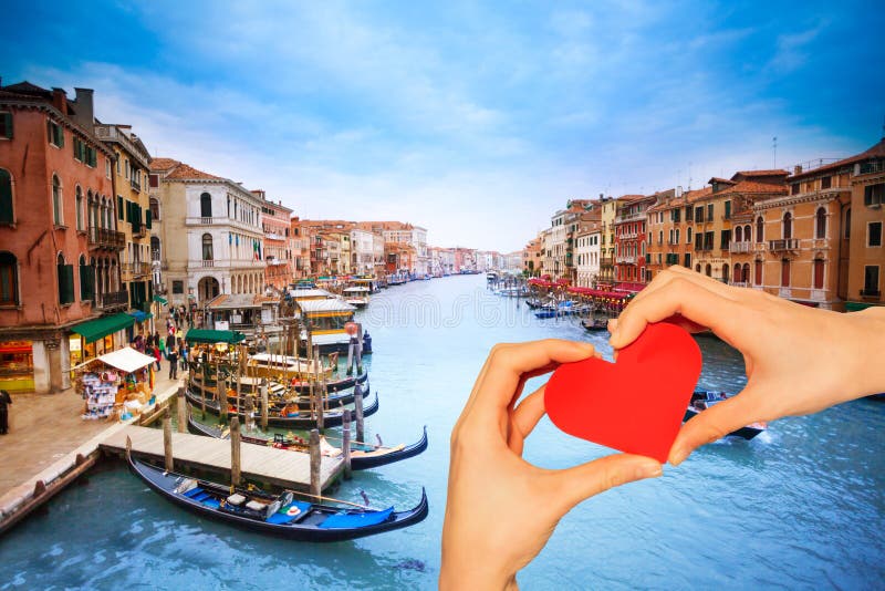 Hand hold red heart over Grande canal in Venice