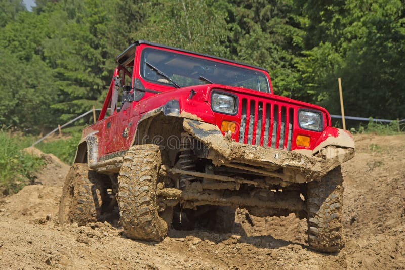 Red off-road vehicle in muddy terrain.
