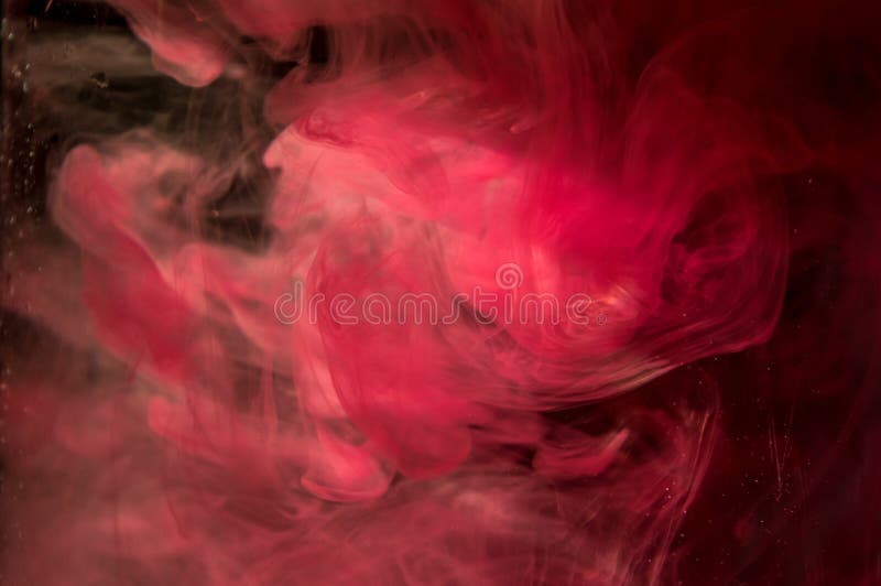 Red ink in water. Sunshine lighting. Dynamic movement of paint in the water. Black background. Red ink in water. Sunshine lighting. Dynamic movement of paint in the water. Black background.