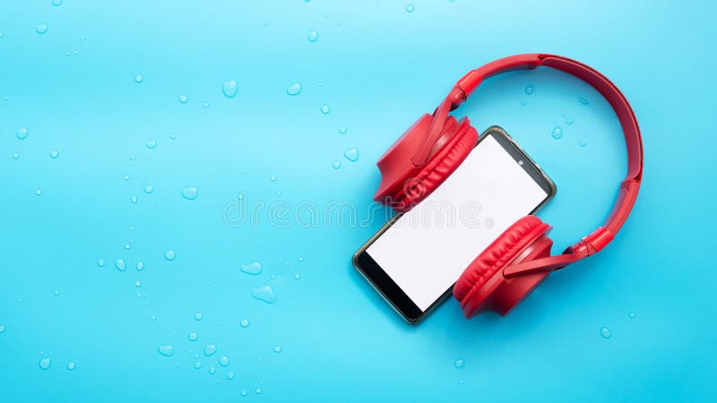 Red overhead music headphones with a smartphone with a white display copy space. Urban, Headphones with a gadget on a blue stock photography