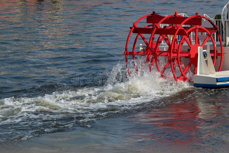 Red paddle wheel on a boat churning the water