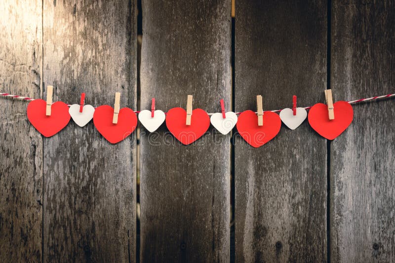 Red paper heart hanging on the clothesline. On old wood background. Valentine Concept