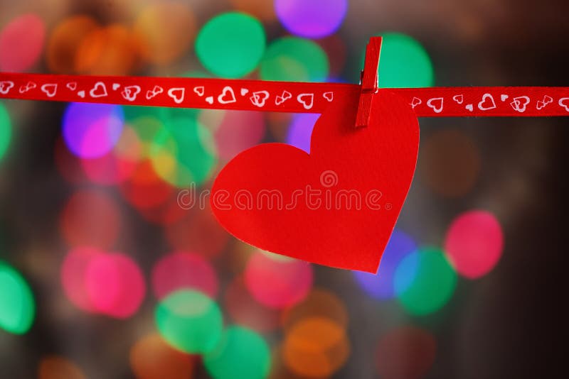 Red Paper heart hanging on red ribbon on colorful background. Concept Valentines day