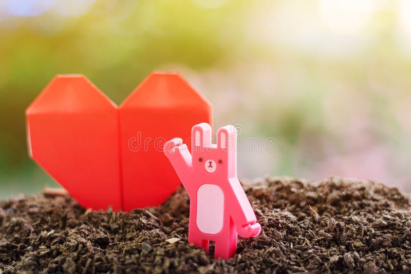 Red paper heart origami with rabbit toy on the soil against blur royalty free stock photos Red paper heart origami with rabbit toy on the soil against blur royalty free stock photos