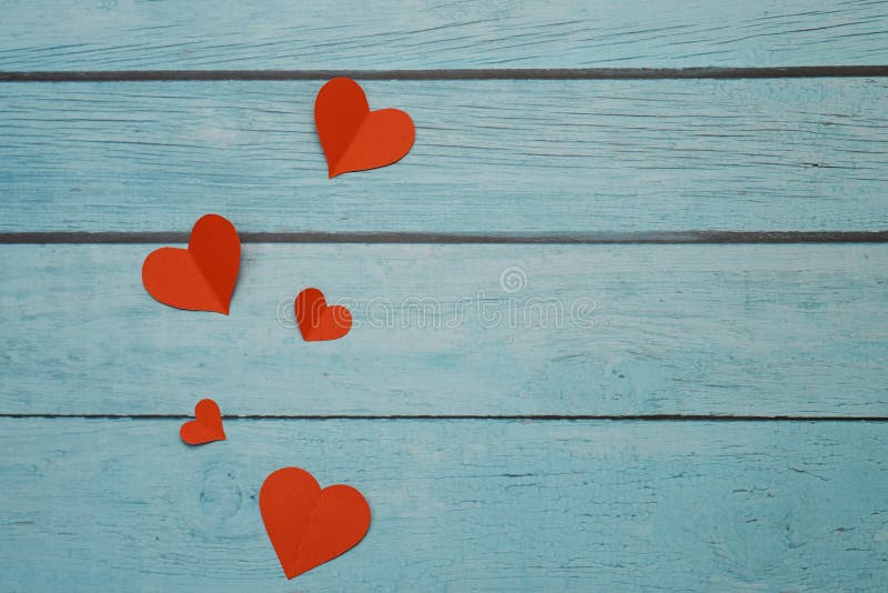 Red paper hearts on a blue wooden background