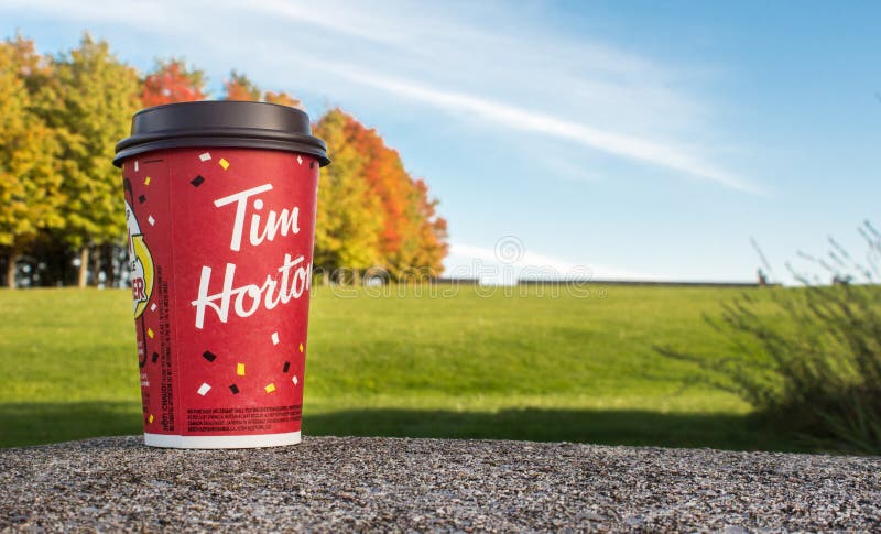 Red Paper Tim Hortons cup of coffee Winning game cup autumn trees on background. Fresh morning coffee. Ottawa, ON, Canada - 20.10.