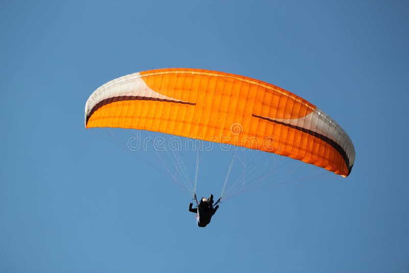 Red paraglider in deep blue sky