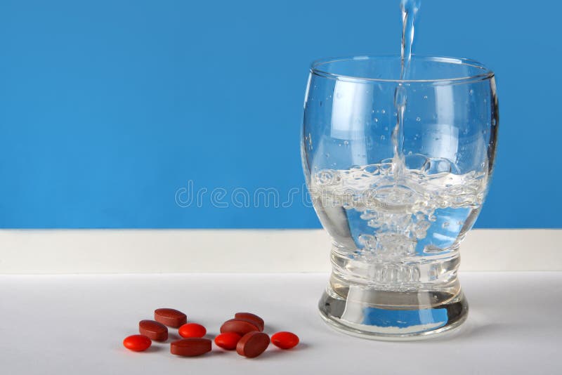 Red pills with water glass