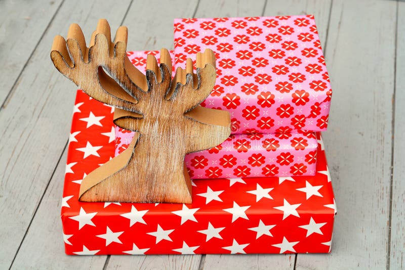 Red and pink star flower pattern christmas gifts with wooden reindeeron a wooden shelves background royalty free stock photography Red and pink star flower pattern christmas gifts with wooden reindeeron a wooden shelves background royalty free stock photography