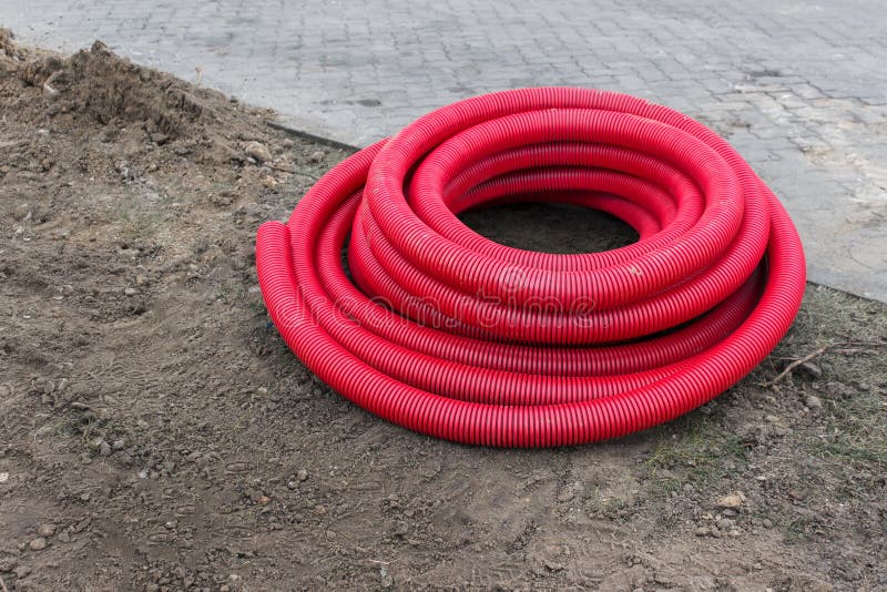 Red Plastic Pipes for Underground Construction Laying on the Ground