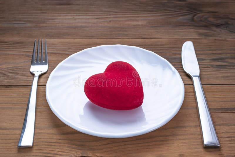 Red Plush Heart on a White Plate with Fork and Knife on Wooden Background. Minimalist Healthcare Symbol. Valentine`s Day, Romanti royalty free stock photos Red Plush Heart on a White Plate with Fork and Knife on Wooden Background. Minimalist Healthcare Symbol. Valentine`s Day, Romanti royalty free stock photos
