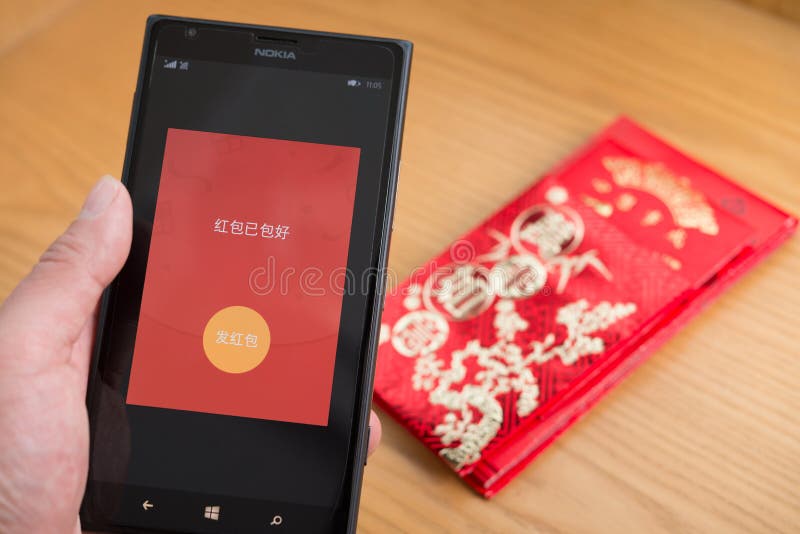 A red pocket on mobile is ready to be sent out on WeChat for Chinese new year with real red pockets on background