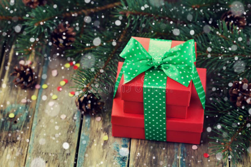 Red present box with bow ribbon decoration of fir tree and conifer cone with magic snow effect on wooden rustic board stock photography Red present box with bow ribbon decoration of fir tree and conifer cone with magic snow effect on wooden rustic board stock photography