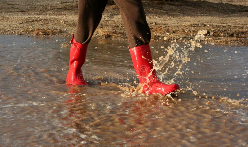 Red rain boots splashing around in mud puddle. Red rain boots splashing around in mud puddle