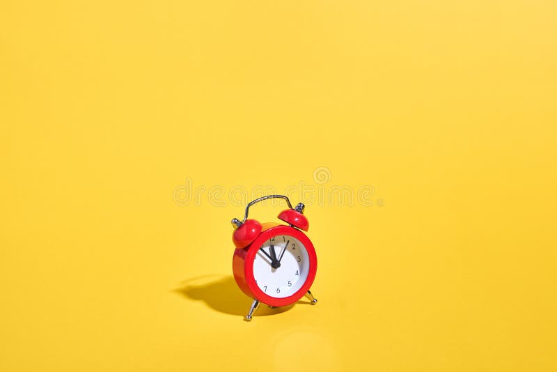 Red retro alarm clock on yellow background. Minimal time concept. Christmas or New year eve.
