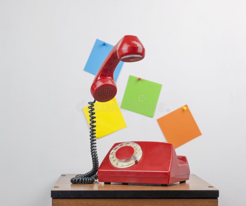 Red retro telephone on wooden nightstand