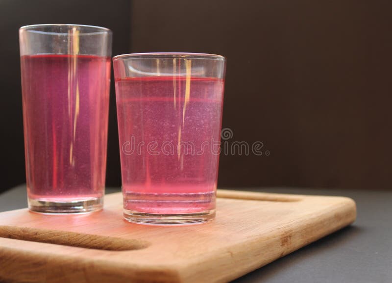 Homemade mors juice compote red pink from alina strawberry blueberries in glasses stand on a board tray on a black background. Homemade mors juice compote red pink from alina strawberry blueberries in glasses stand on a board tray on a black background.