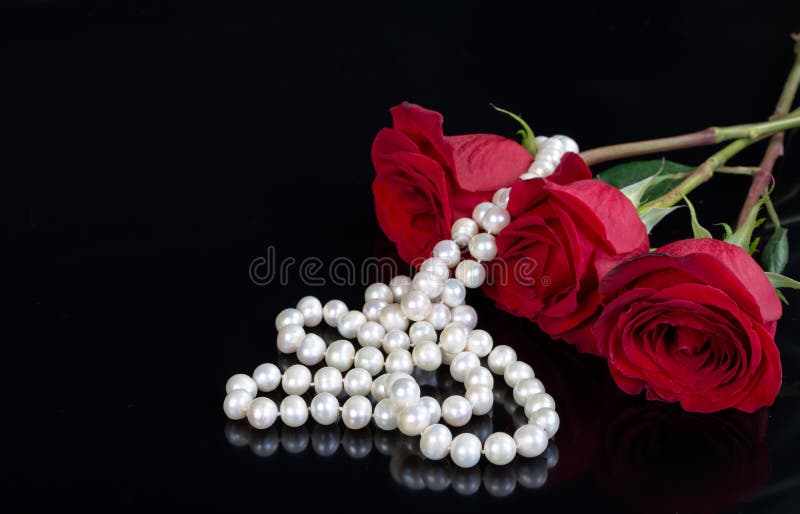 Red rose and pearls on black background