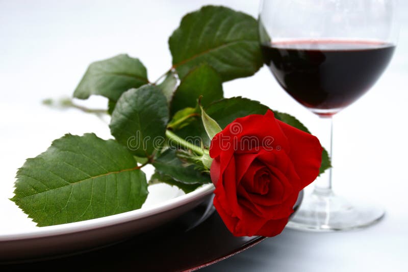 Večera nastavenie s red rose a červené víno.