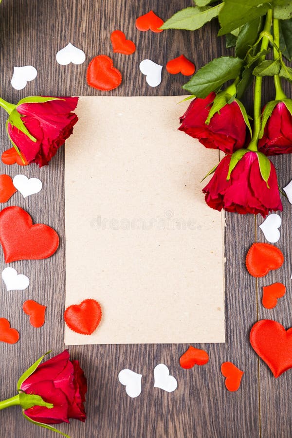 Red roses and card on a wooden background.