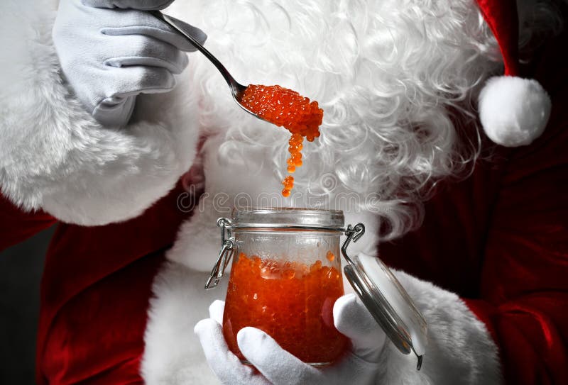 Closeup of a spoon full of red caviar falling back in a jar in Santa Claus hands in white gloves. New Year and Christmas stock images Closeup of a spoon full of red caviar falling back in a jar in Santa Claus hands in white gloves. New Year and Christmas stock images
